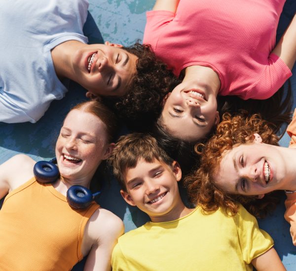 Group of happy teenagers kids outdoors on the sportive field at daytime